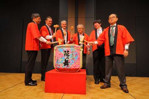 Group of people performing a traditional sake barrel ceremony.