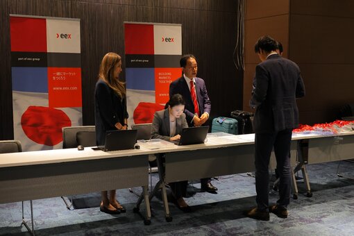Event registration desk with laptops and EEX banners in the background.