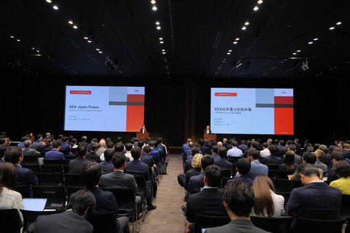 Conference audience listening to a presentation with two large screens.