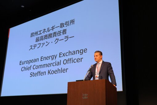 Person standing at a microphone giving a presentation with a slide behind it.